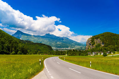 Road amidst green landscape against sky