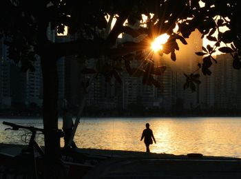 Silhouette woman in city against sky during sunset