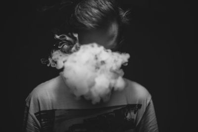 Man emitting smoke against black background