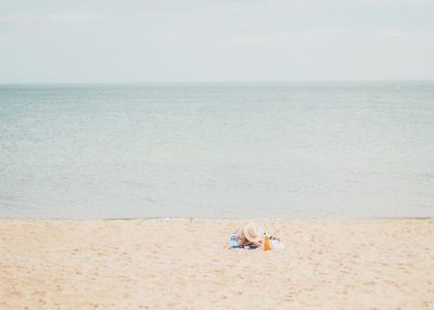 Woman relaxing on beach against sky