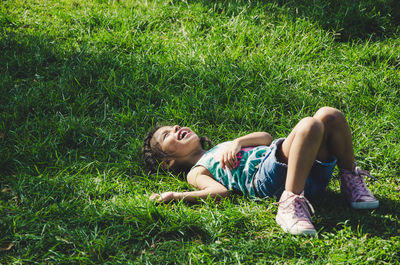 Girl laughing while lying on grassy field