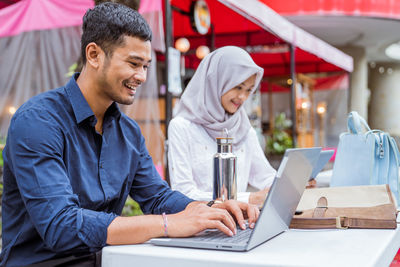 Portrait of man using laptop while sitting in cafe