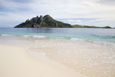 Scenic view of beach against cloudy sky