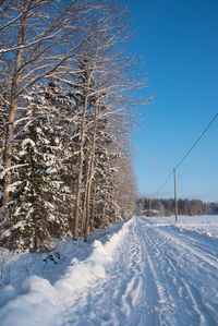 Snow covered road passing through field