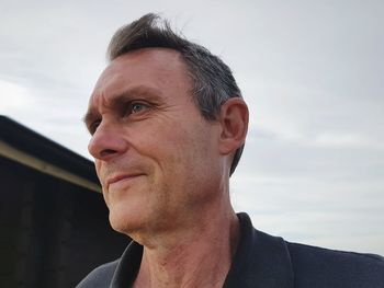 Low angle view of senior man looking away against cloudy sky