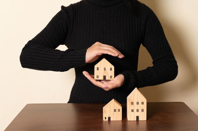 Midsection of woman holding model house on table