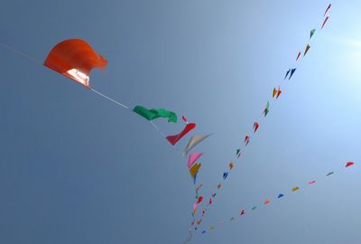 Low angle view of colorful flags hanging against clear sky