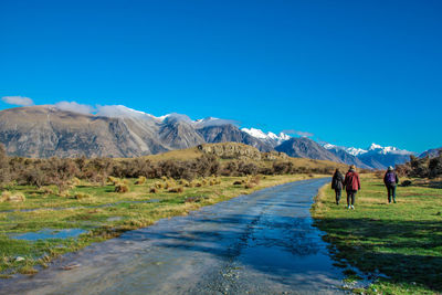 People on mountain road against clear blue sky