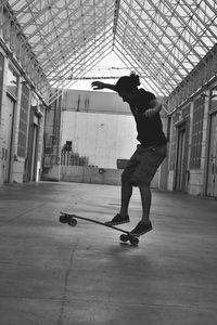 Full length of man skateboarding in empty factory