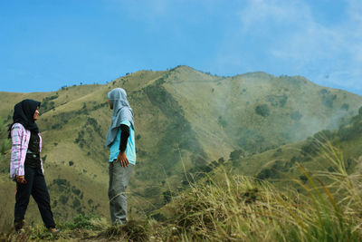 Rear view of women walking on mountain against sky