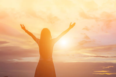 Silhouette woman standing by tree against sky during sunset