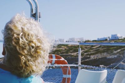 Rear view of boy on boat against sky