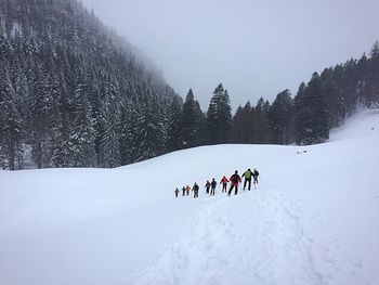 People skiing on snow covered landscape during winter