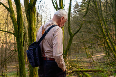 Man standing by tree trunk in forest