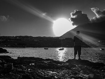 Rear view of man standing at beach against sky