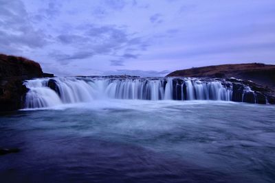 Scenic view of waterfall against sky