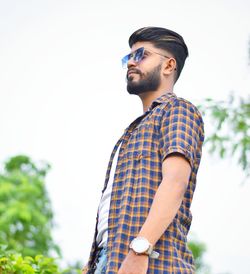 Young man looking away against sky