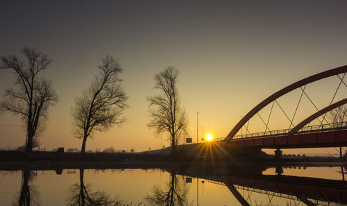 Bridge over river against sky during sunset