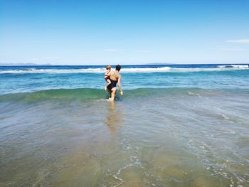 Full length of friends standing on beach against sky