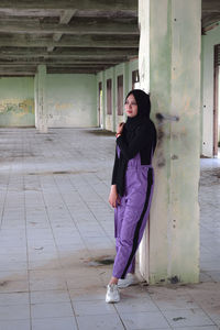 Full length portrait of woman standing against building