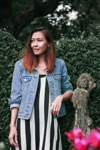 Portrait of beautiful young woman standing against plants