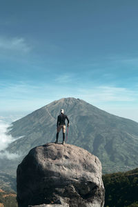 People standing on rock against mountain. mount merapi, indonesia