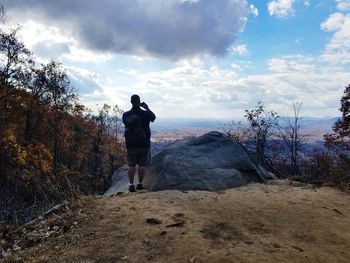 Rear view of man standing on landscape against sky