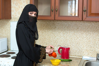 Portrait of young woman standing in kitchen