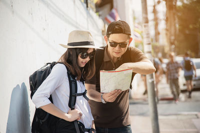 Man discussing map with woman while standing in city
