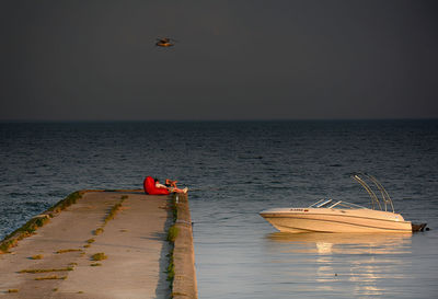 Boat sailing on sea against sky at sunset