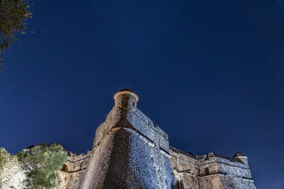 Low angle view of old building against clear blue sky at night