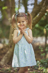 Portrait of young woman standing against trees