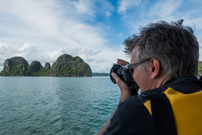 Man photographing sea against sky