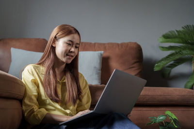 Portrait of young woman using laptop at home