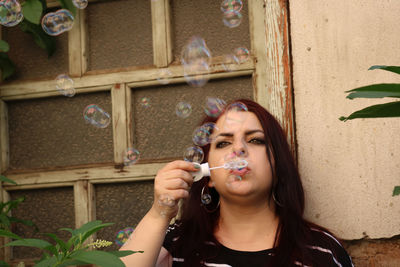 Young woman blowing bubbles at home