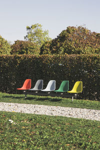 Deck chairs on field against trees in park