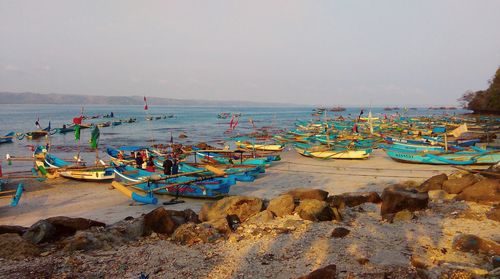 Boats moored on shore at beach against sky