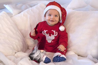 Portrait of cute baby girl sitting on bed