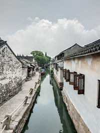 Canal amidst houses and buildings against sky