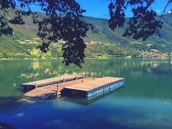 Deck chairs on lake against sky