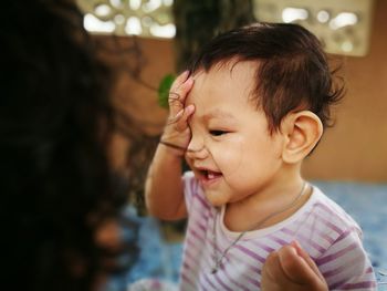 Close-up of cute baby playing peekaboo