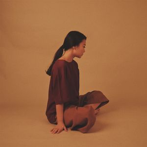 Side view of young woman sitting over brown background