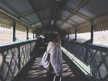 Young woman walking on covered bridge at railroad station
