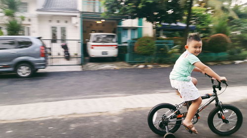 Full length of smiling man with bicycle on street