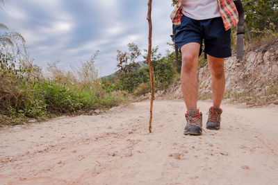 Low section of man walking with stick on dirt road