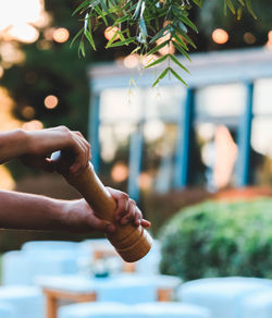 Cropped hands of man holding pepper mill at outdoor restaurant