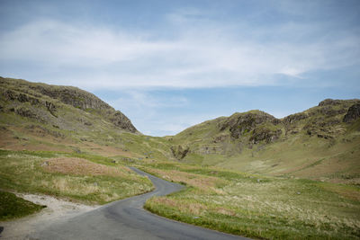 Road leading towards mountains against sky