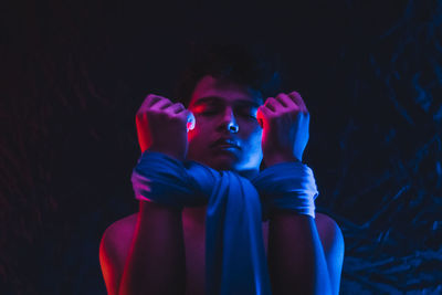 Portrait of young man looking away against black background