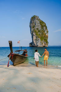 Full length of couple embracing on beach against sky