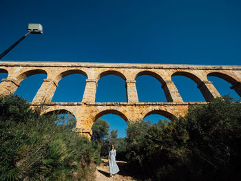 Low angle view of arch bridge against clear blue sky